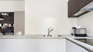 A modern kitchen with a stainless steel sink, a coffee maker, and a built-in oven.