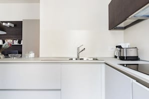 A modern kitchen with a stainless steel sink, a coffee maker, and a built-in oven. - Ca' Moro - Salina (Venice)