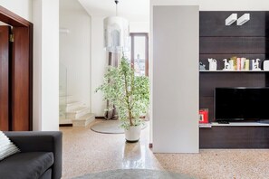 A modern living room with a sofa, a potted plant, a television, and a bookshelf. - Ca' Moro - Salina (Venice)