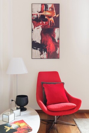 A modern room with a red armchair, a white lamp, and a black bowl on a side table. - Ca' Moro - Salina (Venice)