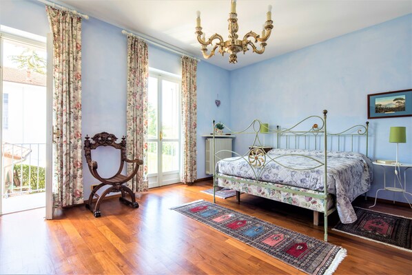 A bedroom with a bed, a chandelier, a desk, and a view of the outdoors. - Villa Mezzaluna with private pool, A/C, Wi-fi on the Langhe hills, 5km from Alba (Scaparoni)