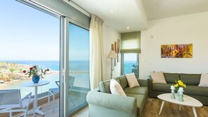 A modern living room with a large sliding glass door leading to a balcony with a view of the beach. - Premium Beachfront Villa With Private Pool & Panoramic Sea Views From Any Angle (Rethymno)