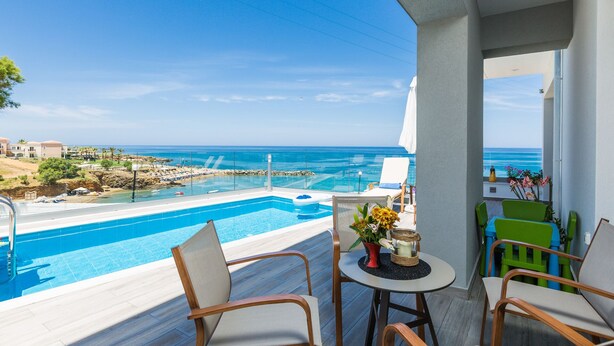 A balcony with a pool, chairs, and a table with flowers. - Premium Beachfront Villa With Private Pool & Panoramic Sea Views From Any Angle (Rethymno)