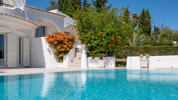 A clear blue swimming pool with white walls and steps leading up to a white building with shutters. - Fabulous spacious villa [57] (Lagos)