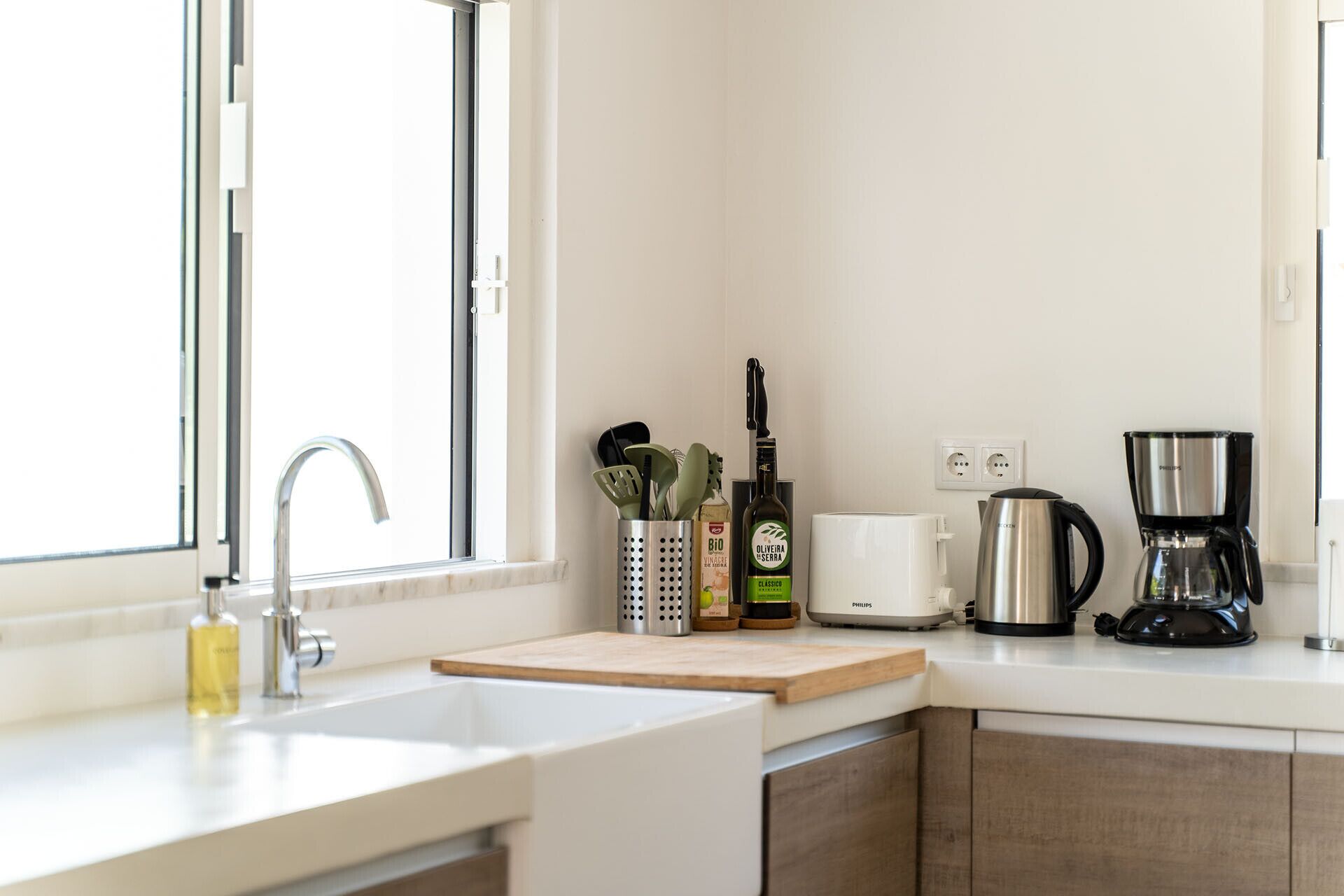 A modern kitchen with a sink, countertop, and various appliances including a coffee maker and a kettle.