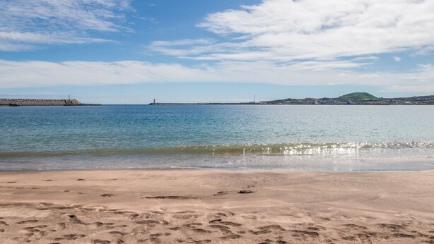 Una playa con cielos despejados y aguas tranquilas.