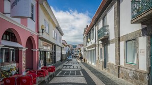 Una estrecha calle adoquinada flanqueada por edificios, algunos con balcones y otros con tiendas.