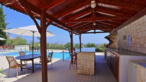 An outdoor pool area with a covered seating area, a bar, and a view of the pool. - Villa Mandola Rosa: Elegantly decorated, sea views, pool, A/C (Prodromi Latchi)