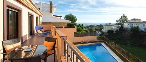 A balcony with a pool, outdoor furniture, and a view of the surrounding landscape.