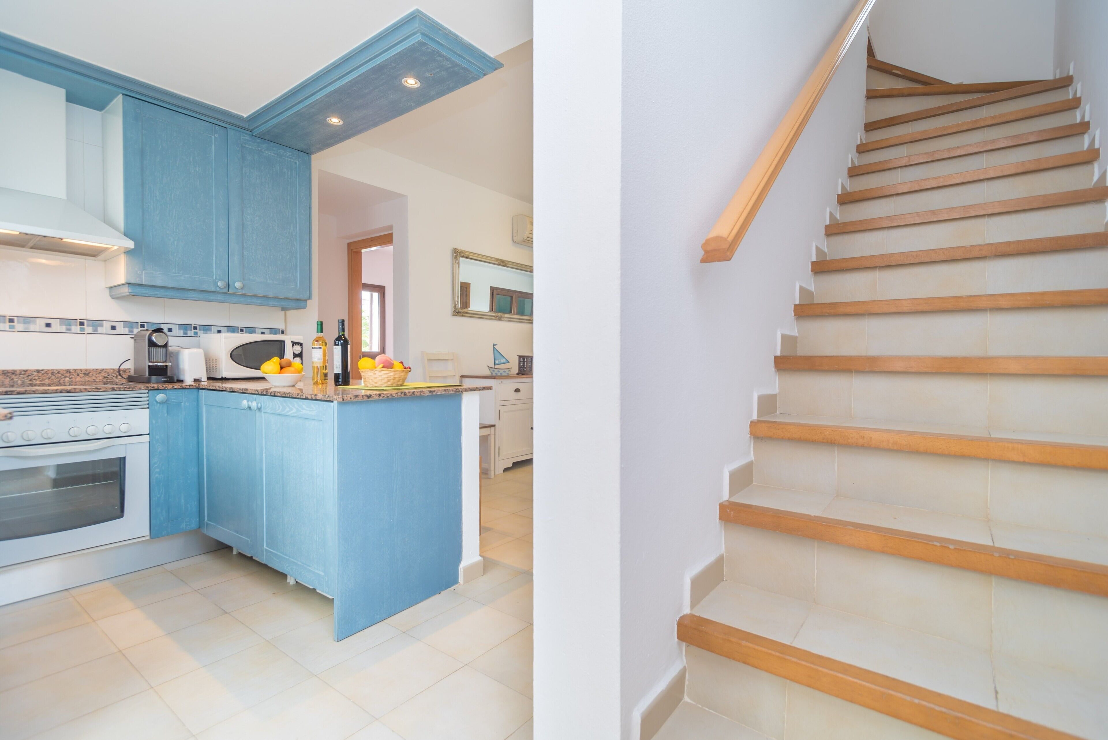Une cuisine moderne avec des meubles bleus, un îlot central et un escalier en bois.