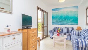 A living room with a television, a sofa, a coffee table, and a painting of a wave. - MARINA D'OR IV CASA 5 - Chalet with shared pool in Cala D'Or. Free WiFi (Santanyí)