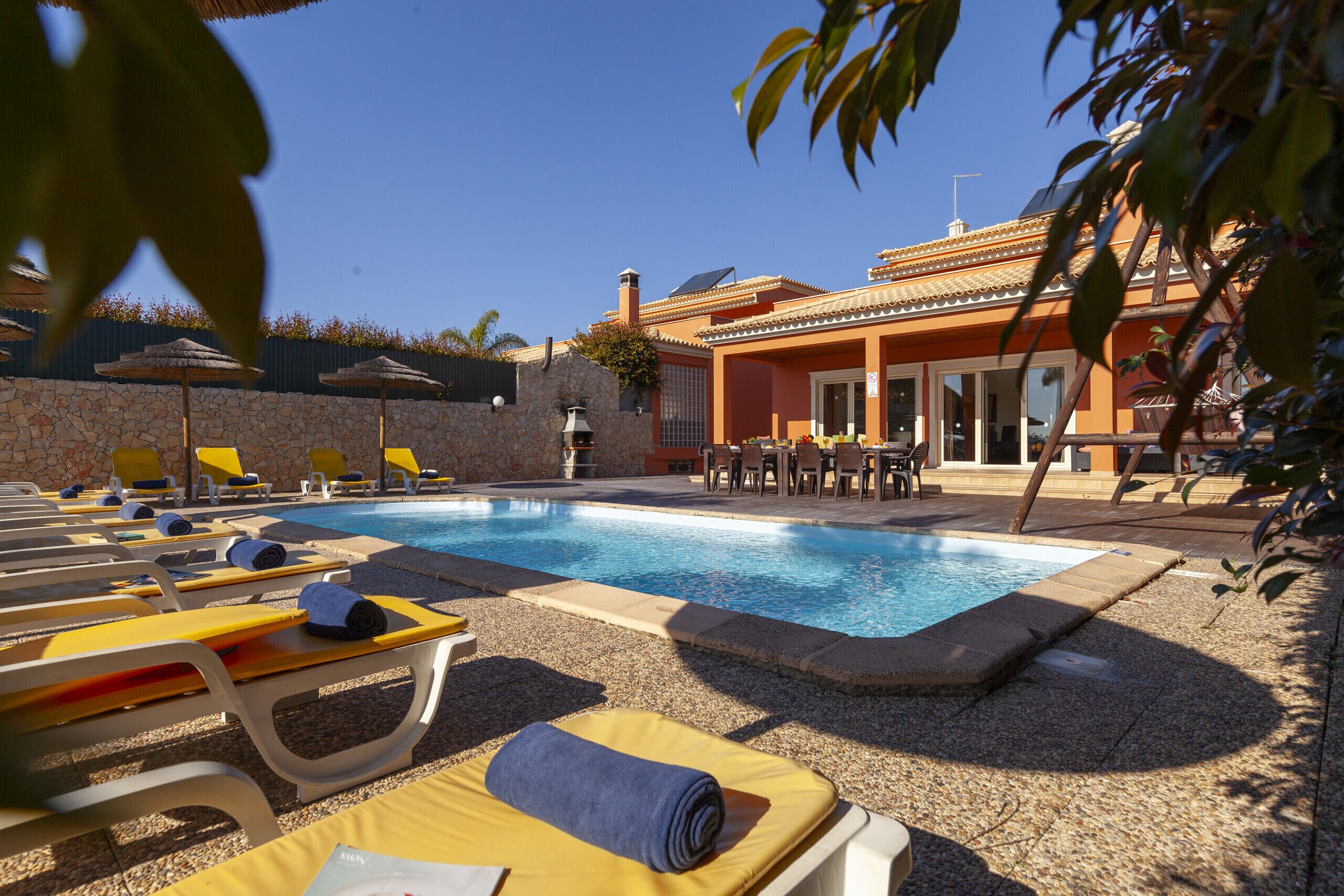 Un espace piscine avec des chaises longues et un mur en pierre.