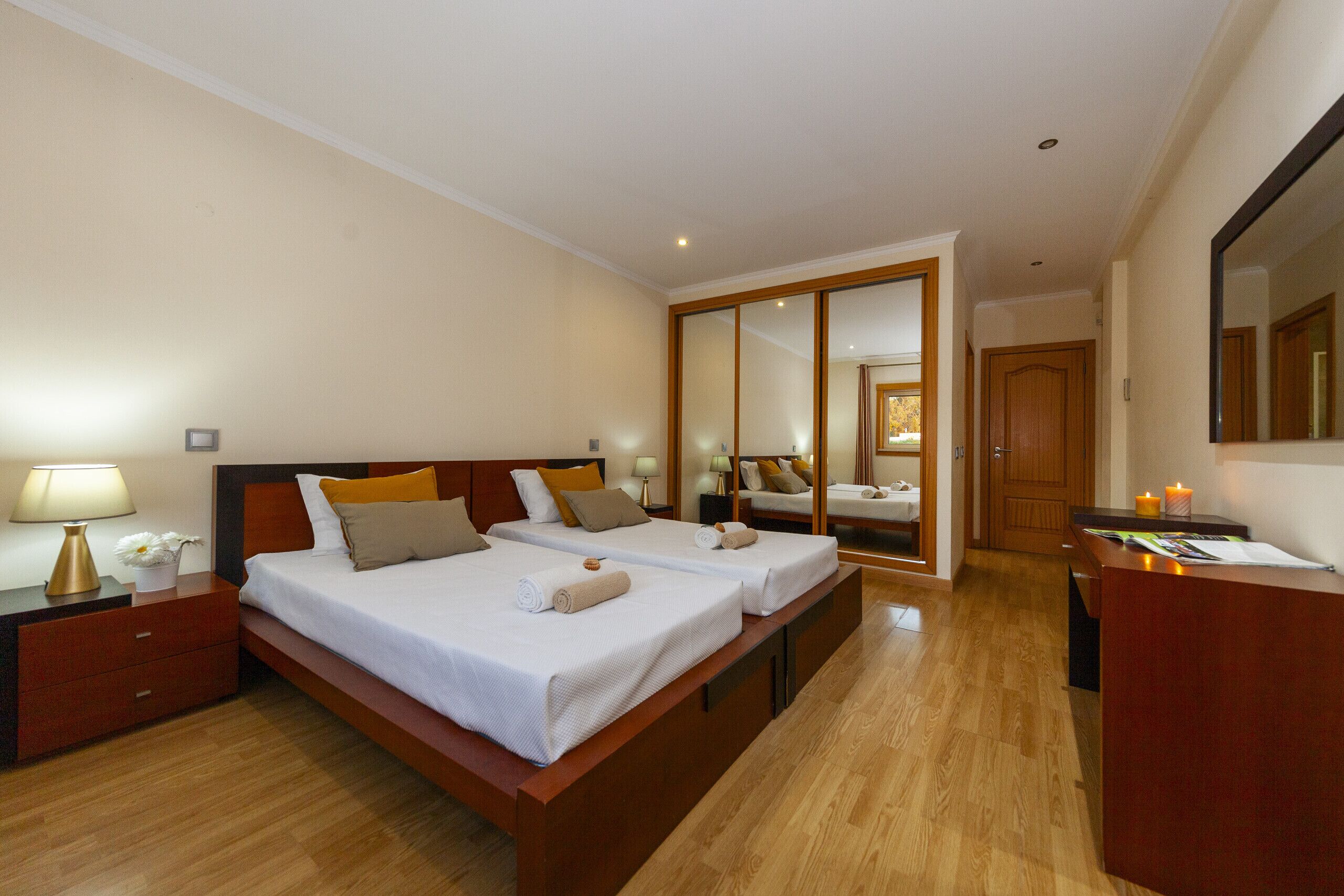 Une chambre d’hôtel avec deux lits, un plancher en bois, un bureau et un miroir.