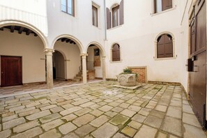 A courtyard with stone paving, arched doorways, and a small planter. - Ca' Moro - Murano (Venice)