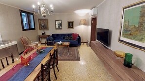 A living room with a sofa, television, dining table, chairs, and a chandelier. - Ca' Moro - Murano (Venice)