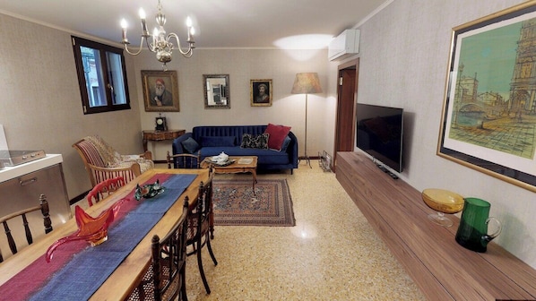 A living room with a sofa, television, dining table, chairs, and a chandelier. - Ca' Moro - Murano (Venice)