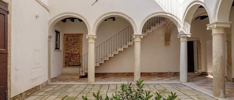 Un cortile con una scala, archi e pavimento piastrellato.