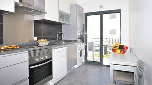 Een moderne keuken met roestvrijstalen apparatuur, een inbouwoven en een wasmachine.