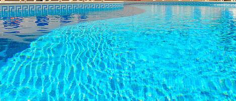 Ein klares Schwimmbecken mit blauem Wasser, umgeben von Liegestühlen.