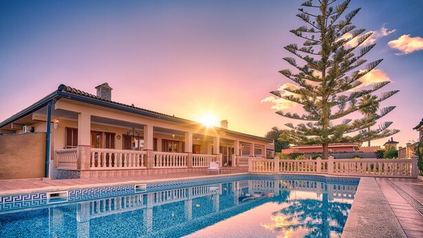 A pool with a geometric tile pattern, a large tree, and a building with a balcony and a covered patio area. - Beautiful villa with private pool excelent for families. Aircond and wifi available - Free Wifi (Llucmajor)