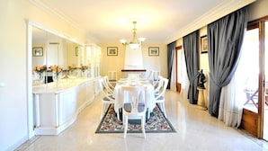 A dining area with a white table, chairs, and a chandelier. There are framed pictures on the walls and a mirror on the left. - Beautiful villa with private pool excelent for families. Aircond and wifi available - Free Wifi (Llucmajor)