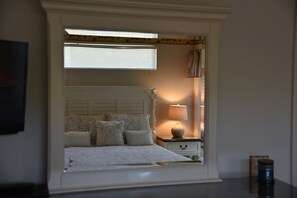 Relax in this serene bedroom with a comfortable bed, bedside table, and stylish mirror.