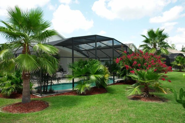 Relax in a serene outdoor space surrounded by lush greenery and a swimming pool.