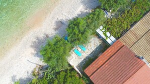 Une vue aérienne d’une plage avec une eau cristalline, une piscine et un bâtiment doté d’un toit rouge.