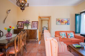 Un comedor con una mesa y sillas de madera, un sofá y un cuadro en la pared.