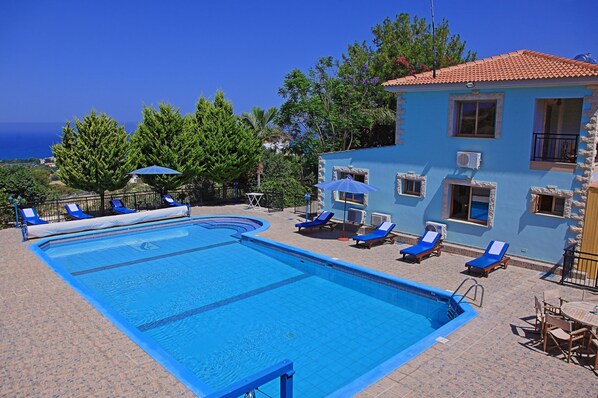 Una piscina con piastrelle blu, circondata da sdraio e ombrelloni.