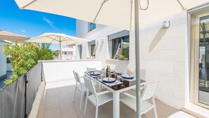 A terrace with a table set for dining, outdoor umbrellas, and a view of neighboring buildings. - FORMENTERA 1 - Modern terraced house near the beach. Free WiFi (Muro)