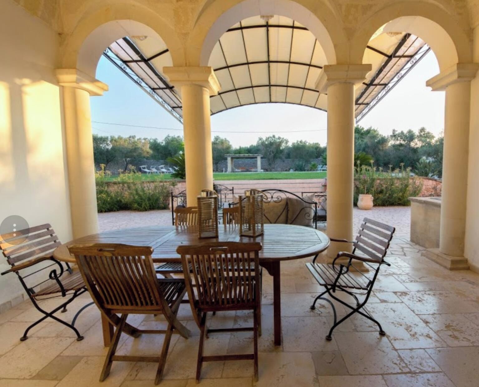 A covered outdoor dining area with a view of a park.