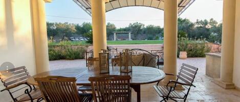 A covered outdoor dining area with a view of a park.