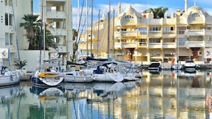 Una marina con diverse imbarcazioni ormeggiate, un edificio dall'architettura a cupola e un cielo sereno.