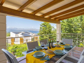 A dining area with a table set for two, overlooking a scenic view of a body of water and mountains. - Villa Heura· Villa with private pool in Alcúdia (Alcúdia)