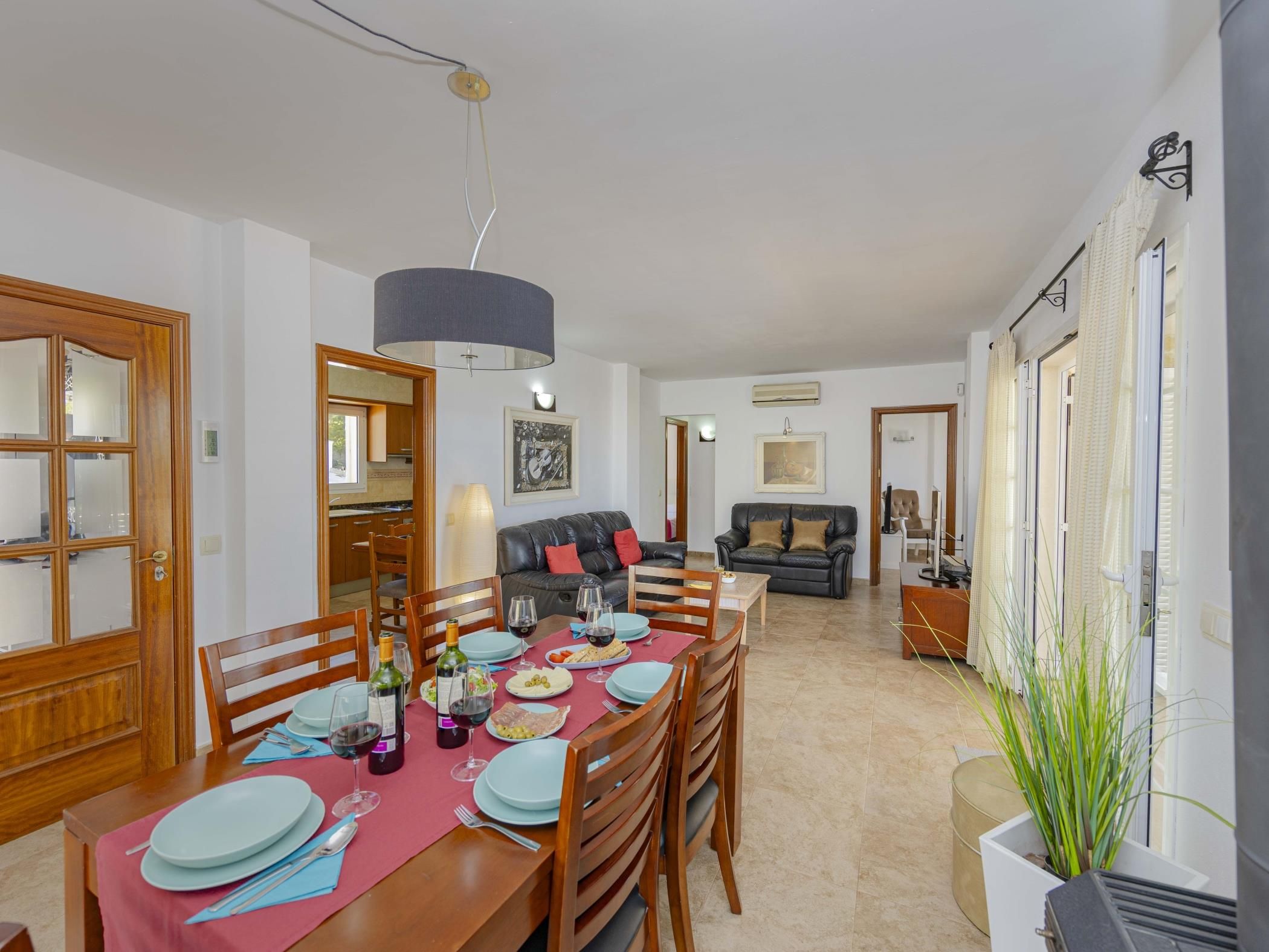 A dining area with a wooden table set for a meal, a sofa, and a lamp.