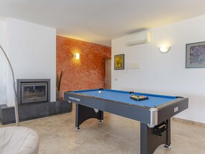 A pool table in a room with a fireplace, a wall-mounted air conditioner, and a framed picture. - Villa Heura· Villa with private pool in Alcúdia (Alcúdia)