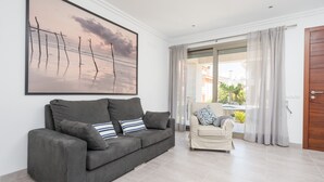 En moderne stue med en grå sofa, en beige lænestol og et stort billede i ramme af en strand.