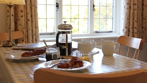 Une table de petit-déjeuner avec des croissants, du café et une carafe de jus de fruits.
