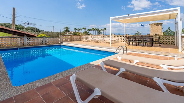 Une piscine avec des chaises longues, un espace de détente couvert et une vue sur le paysage environnant.