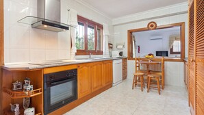 Une cuisine avec des meubles en bois, un lave-vaisselle et un coin repas comprenant une table et des chaises.