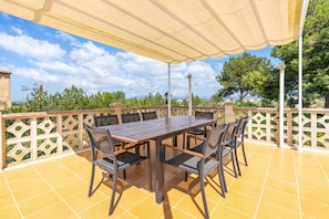 An outdoor patio with a table and chairs, a pergola, and a view of trees and mountains.