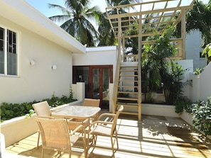 Relax in a serene outdoor space surrounded by lush greenery and a wooden pergola.