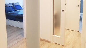 Un dormitorio con cama, una puerta y vista al baño.