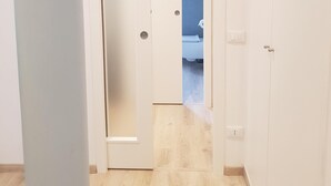 Un pasillo con piso de madera que lleva a una puerta blanca con un panel de vidrio esmerilado.