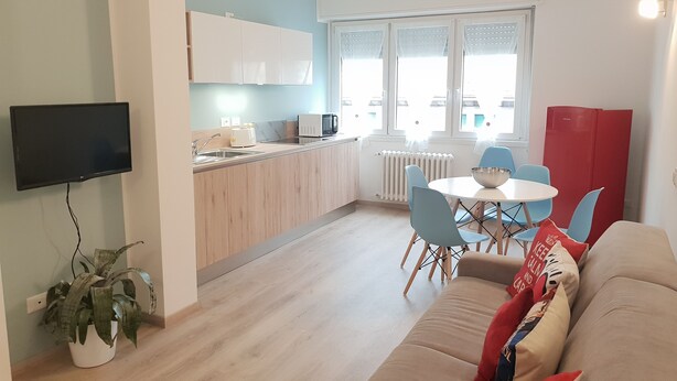 Una cocina moderna con comedor, un televisor de pantalla plana y una planta en maceta.
