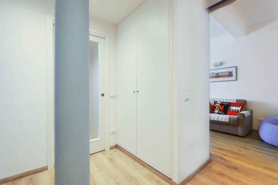 A room with a wardrobe, a sofa, and a bed.
