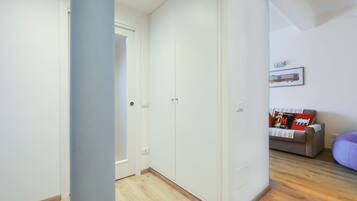 A room with a wardrobe, a sofa, and a bed.