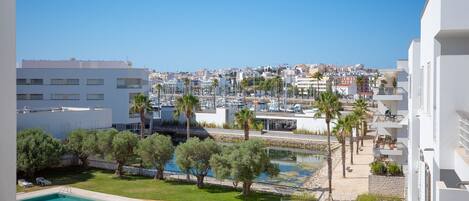 A balcony with a view of a marina, a swimming pool, and surrounding buildings.