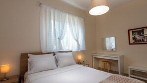 Un dormitorio con cama, lámparas de noche, escritorio, espejo y ventana con cortinas.